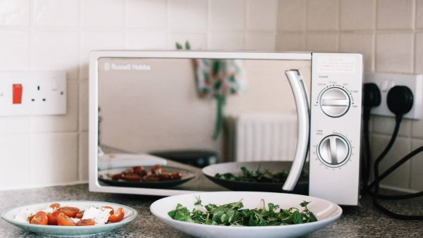 two white ceramic plates near microwave on counter top